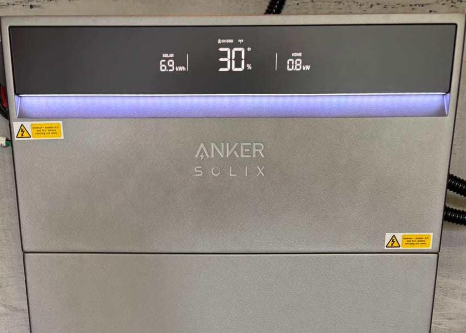A wall-mounted home battery showing a live display: 6.9 kWh of solar generated, 30 per cent charged and 0.8 kW being drawn by the house