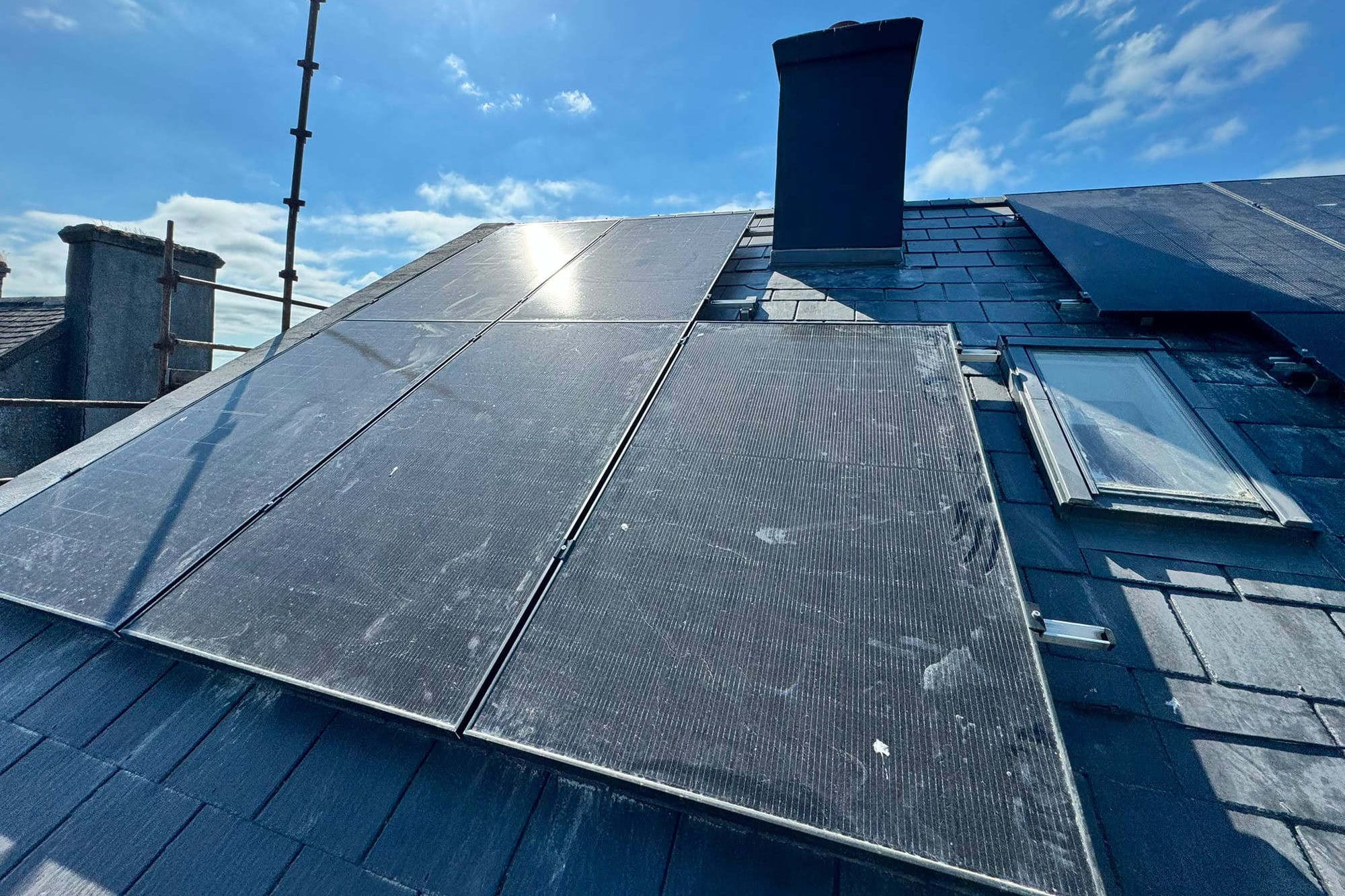 A completed domestic array on a slate roof, panels fitted either side of the chimney